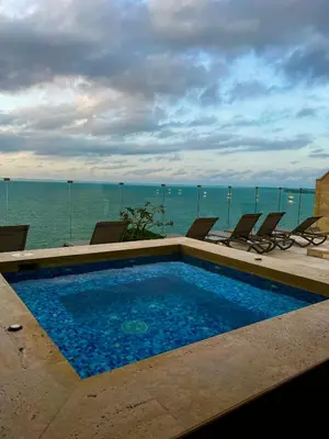 a swimming pool with chairs and the ocean in the background at Hermoso apartamento con vista al mar y salida directa a la playa in Cartagena de Indias