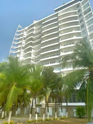 a large white building with palm trees in front of it at Hermoso apartamento con vista al mar y salida directa a la playa in Cartagena de Indias