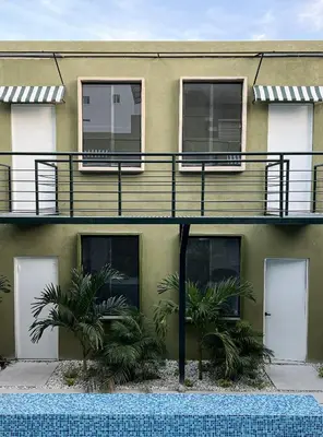a building with a balcony and palm trees in front of it at OASIS TROPICAL HOTEL in Santa Marta