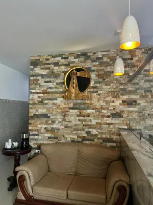 a couch against a brick wall with a clock on it at Hotel El Faro - Desayunos incluidos - Manga, Cartagena in Cartagena de Indias