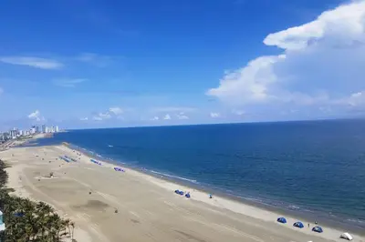 a beach with people and umbrellas and the ocean at Cerca al Hotel Americas Ctgna Spiaggia Morros Piscina playa in Cartagena de Indias