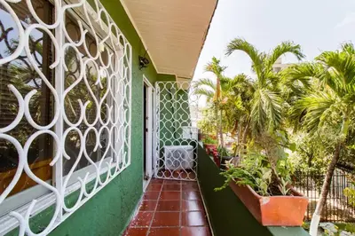 a balcony with a green and white fence and palm trees at Casa Verde El Golf in Barranquilla
