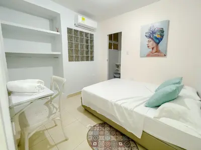 a white bedroom with a bed and a table at 3CB-2 APARTAMENTO DE 3 ALCOBAS EN EL CENTRO HISTORICO CON AIRE ACONDICIONADO Y WIFI in Cartagena de Indias