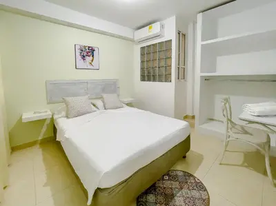 a white bedroom with a large bed and a desk at 3CB-2 APARTAMENTO DE 3 ALCOBAS EN EL CENTRO HISTORICO CON AIRE ACONDICIONADO Y WIFI in Cartagena de Indias