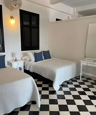 two beds in a white room with a checkered floor at 704 Puesta de sol apto en Cartagena in Cartagena de Indias