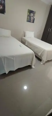 two beds in a white room with a picture on the wall at Hermosa casa amoblada in Barranquilla