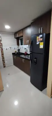 a kitchen with a black refrigerator and wooden cabinets at Hermosa casa amoblada in Barranquilla