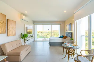 a bedroom with a bed and a couch and a table at Lujoso Apto Cartagena - Acceso Directo a la Playa in Cartagena de Indias