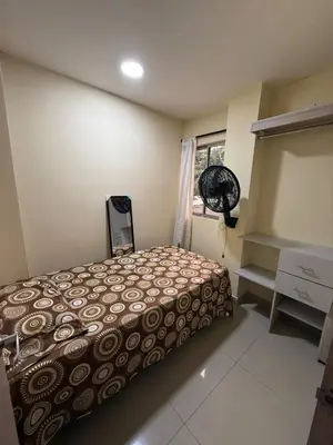 a bedroom with a bed and a window with a fan at Apartamento en el epicentro del Carnaval in Barranquilla