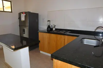 a kitchen with a black counter and a refrigerator at Cabaña Macondo in Coveñitas