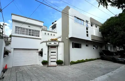 a white house with a car parked in front of it at Hostal Casa Marle in Puerto Colombia