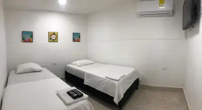 two beds in a room with white walls at Martinica Hostel in Cartagena de Indias