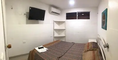 a bedroom with a bed and a tv on the wall at Martinica Hostel in Cartagena de Indias
