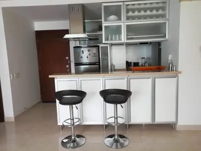 a kitchen with white cabinets and two black stools at APARTAMENTO MORROS922 LA BOQUILLA con acceso directo a la Playa in Cartagena de Indias