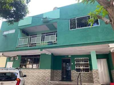 a green house with a car parked in front of it at HOTEL LOS GUADUALES in Barranquilla