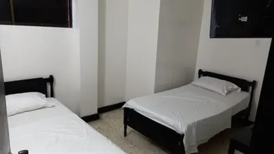two twin beds in a room with white walls at HOTEL LOS GUADUALES in Barranquilla