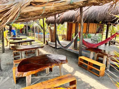 a restaurant with tables and chairs and a hammock at Arcoiris EcoHotel in San Bernardo del Viento