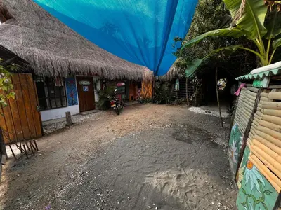 a dirt road next to a building with a straw roof at Arcoiris EcoHotel in San Bernardo del Viento