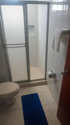 a bathroom with a shower with a toilet and a blue rug at Azul de Bocagrande in Cartagena de Indias