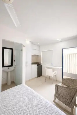 a white bedroom with a bed and a bathroom at Aparta estudios Mubarak in Barranquilla