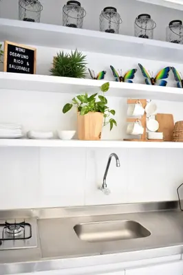 a kitchen with white shelves with plants and a sink at Aparta estudios Mubarak in Barranquilla