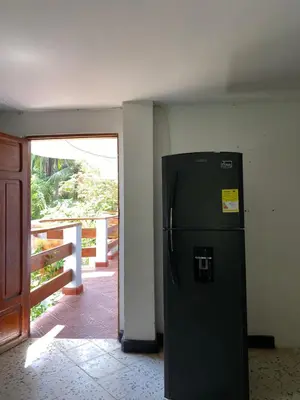 a refrigerator in the corner of a room with a door at Hotel Villa Mary apartaestudios playa in Maizal