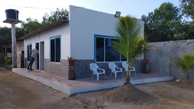 a man standing outside of a house with a palm tree at PLAYA MAG in Coveñas