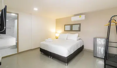 a bedroom with a white bed and a bath tub at Bahari Cartagena Suites in Cartagena de Indias