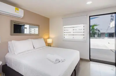 a bedroom with a large white bed and a window at Bahari Cartagena Suites in Cartagena de Indias