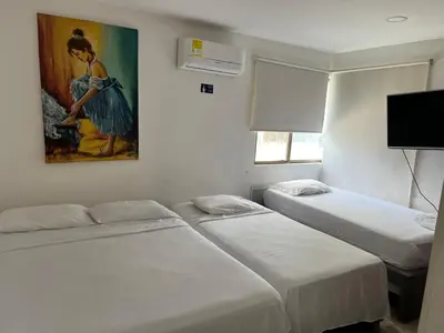 a room with three beds and a painting on the wall at Apartamento con vista al mar in Cartagena de Indias