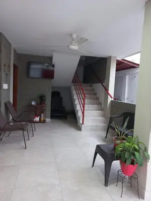 a living room with a staircase and chairs and tables at Rancho Ayala II in Santa Marta