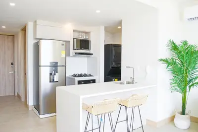 a kitchen with a refrigerator and two bar stools at Apartamento vista al Mar lateral Panoramic View,Spectacular building,Pools, Beach Morros zoe ultimo piso in Cartagena de Indias