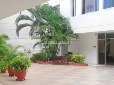 a bench in front of a building with palm trees at Apartamento 1804 Cartagena Bocagrande hermosa vista a 1 cuadra de la playa in Cartagena de Indias