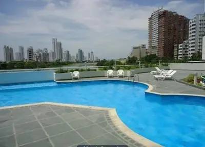 a large blue swimming pool with white chairs and buildings at Apartamento torres del lago 1102 in Cartagena de Indias