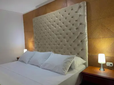 a bedroom with a white bed with a padded headboard at Hotel Prado 72 INN in Barranquilla
