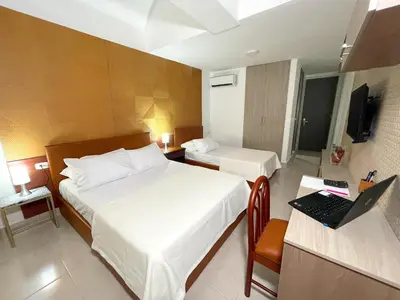 a hotel room with two beds and a laptop on a desk at Hotel Prado 72 INN in Barranquilla