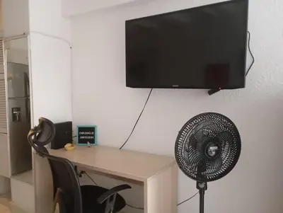 a desk with a fan and a television on a wall at @casa__grace Apartaestudio en edificio al frente del mar!! in Cartagena de Indias