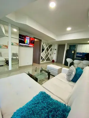 a living room with a white couch and a tv at TU VISTA IDEAL in Cartagena de Indias