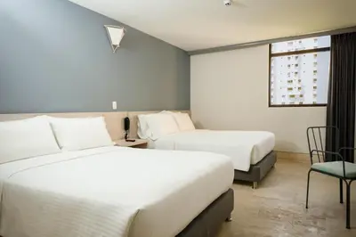 a hotel room with two beds and a chair at Hotel Rilux Cartagena in Cartagena de Indias