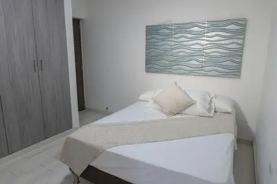 a bedroom with a bed with a painting on the wall at Apartamento en Cartagena cerca al aeropuerto y Playa in Cartagena de Indias