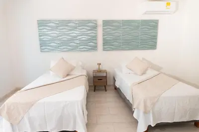 two beds in a room with white walls at Apartamento en Cartagena cerca al aeropuerto y Playa in Cartagena de Indias
