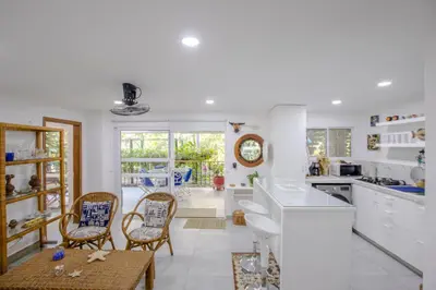 a kitchen with white counters and chairs and a table at Apartamento con salida a la playa in Santa Marta