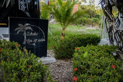 a sign in the middle of a garden with plants at Cabaña los Abuelos in Coveñas