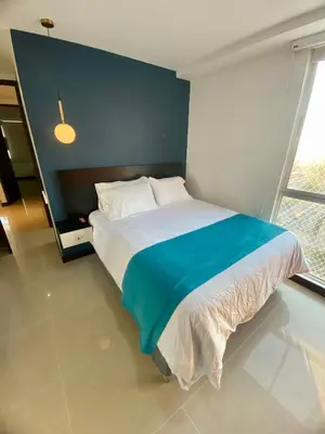 a bedroom with a large bed with a blue wall at Atlantis Suites BAQ -Apartamento Moderno-2-BD in Barranquilla
