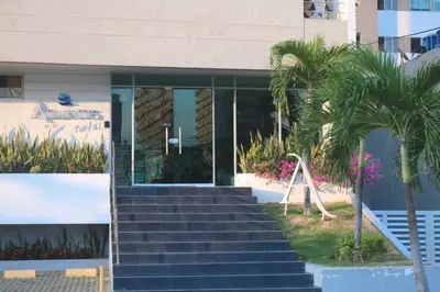 a building with stairs in front of a building with palm trees at Atlantis Suites BAQ -Apartamento Moderno-2-BD in Barranquilla