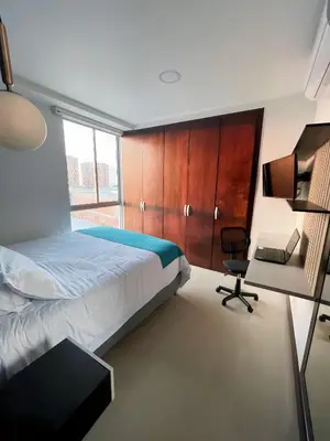 a bedroom with a bed and a desk and a chair at Atlantis Suites BAQ -Apartamento Moderno-2-BD in Barranquilla