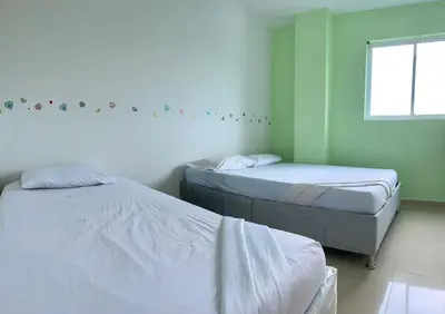 two beds in a room with green walls and a window at Apartamento 405 in Cartagena de Indias