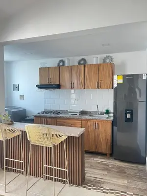 a kitchen with wooden cabinets and a black refrigerator at Coveñas Apartamento vacacional caribe campestre 9-502 in Coveñas