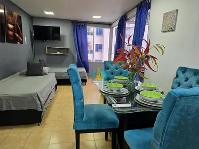 a living room with a table and blue chairs at Apto Vista Lateral Mar Piso 15 in Cartagena de Indias