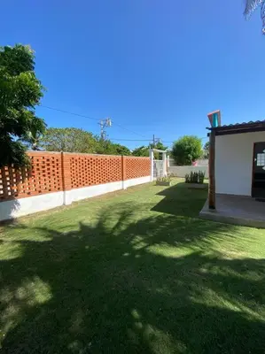 a yard with an orange fence and a green lawn at Cabaña con piscina y Cerca al mar VILLA CONEJO in Juan de Acosta